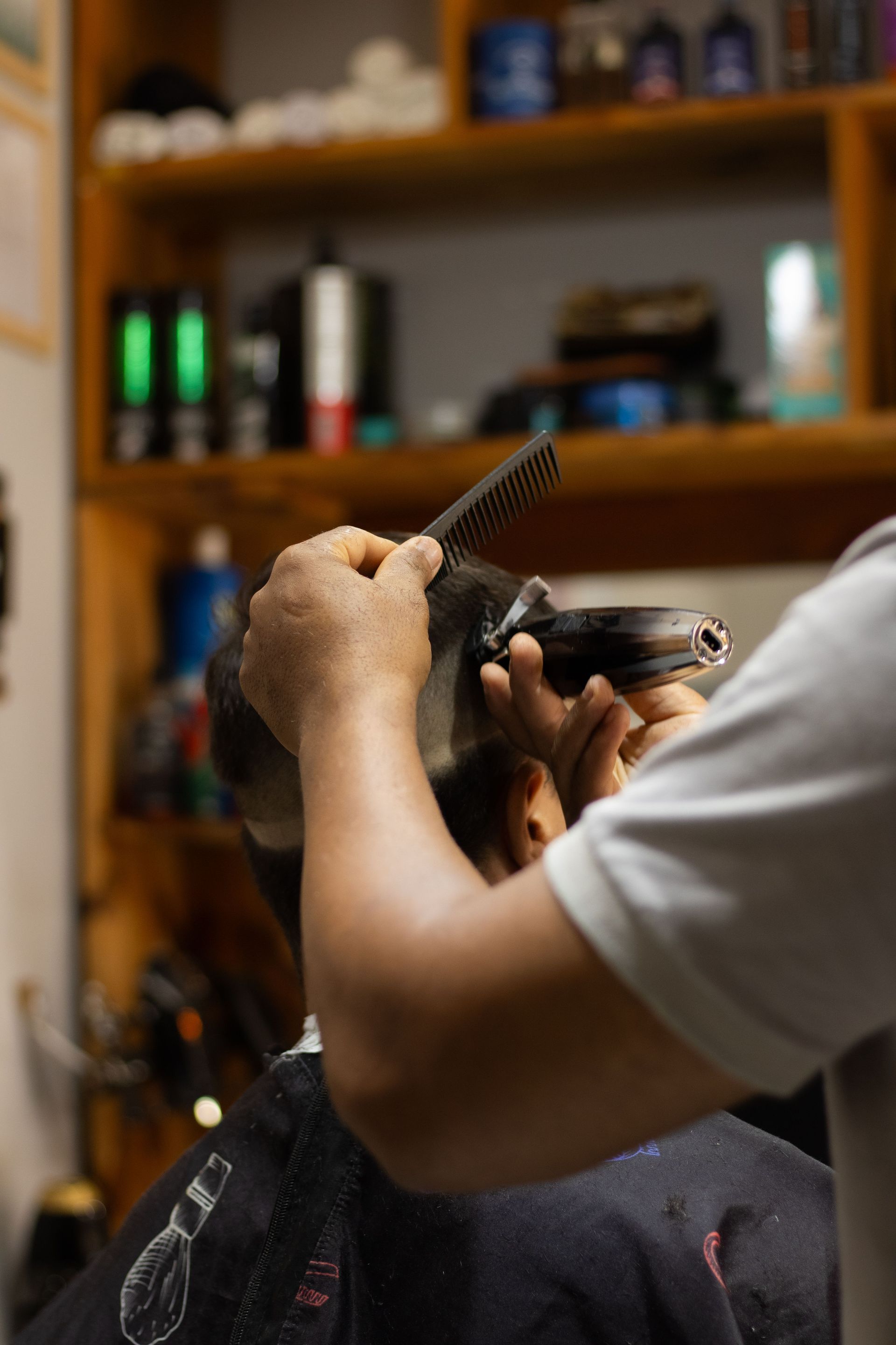 A barber skillfully trims a man's hair using clippers and comb in a barbershop.